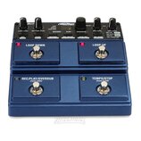 Modrý kytarový looper s čtyřmi stoupacími spínači. Na horní části jsou knoflíky a nápisy LOOP LEVEL, RHYTHM LEVEL, MIC LEVEL a značka JamMan. Spínače…