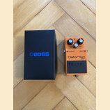 Kytarový efekt v oranžovém provedení s nápisy Distortion DS-1 a logem BOSS. Pedál má tři ovládací knoflíky s popisky TONE, LEVEL a DIST, červenou kon…
