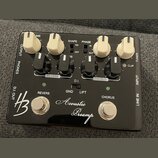 Černý kytarový efekt s nápisem Acoustic Preamp a logem HB. Zařízení má čtyři bílé otočné knoflíky, čtyři černé přepínače a dvě stříbrné tlačítka ozna…