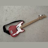 Červená elektrická basová kytara s bílým pickguardem a světlou hnedou hmatníkem. Na hlavě nástroje je viditelné logo "Randy Bass". Kytara má čtyři st…