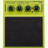 Žlutý elektronický perkusní pedál s černou gumovou dopadovou plochou, na které je vyražené logo Roland. V horní části jsou čtyři otočné ovratky s pop…