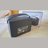 Černý kytarový kombo zesilovač s rukojetí, umístěný vedle původního kartónového obalu. Na krabici je nápis „amplifier KATANA-MINI X“. Na zadní straně…