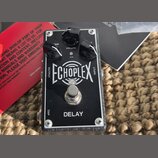 Černý efekt pedál s nápisem ECHOPLEX a DELAY. Na horní straně jsou tři černé otočné ovnovky s popisky GAIN, VOLUME a AGE. V dolní části je umístěn ko…