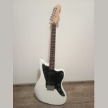 Bílá elektrická kytara s černým plechtrádem a hnědým hmatníkem. Na hlavě je viditelné logo "Stratocaster". Nástroj vykazuje čistý povrch bez viditeln…