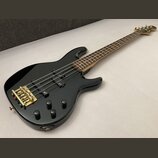 Černá elektrická basová kytara s čtyřstrunným hnedým hmatníkem a zlatým hardwarem. Na obou snímačích i na těle je viditelné logo Fender. Nástroj vyka…