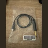 Černý audio kabel s konektory na obou koncích, umístěný v průhledném plastovém sáčku. Jeden konektor je zlatý jack, druhý je stříbrný. Na bílé nálepc…