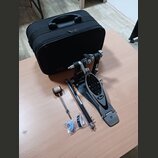 Na fotografii je černý basový pedál s logem Pearl na šlapce a doprovodný černý kufr. K pedálu jsou přiloženy volné části: beater s plstěnou hlavou, k…
