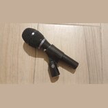 Černý dynamický mikrofon s kovovou mřížkou a držákem. Na těle mikrofonu je vyražen nápis AUDIX. Povrch je matně černý s viditelnými stopami používání…
