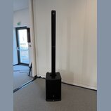 Černý sloukový reproduktor s subwooferem v základně. Na horní části sloupce i na spodní části subwooferu je viditelné logo JBL. Povrch je matný a v d…