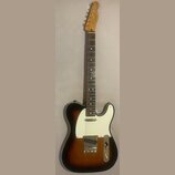 Elektrická kytara s tónem sunburst a bílým pickguardem. Na hlavě hředu je viditelné logo Squier by Fender a nápis CUSTOM TELECASTER. Nástroj je v dob…