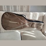 Hnědý softcase na kytaru s černým zipem a úchytkem. Na přední straně je bílý nápis RITTER a malý trojúhelníkový štítek s nápisem RITTER. Povrch texti…