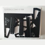 Bílá krabice s nápisem EURORACK STAND (3-TIER) a podtitulem 3-Tier Eurorack Stand for 70, 80 and 104 HP Chassis. Uvnitř jsou rozložené černé kovové d…