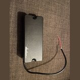 Černý elektrický snímač kytary s matným povrchem. Na spodní části je bílým nápisem logo Jackson. Ze snímače vychází černý kabel s odkrytými červeným…