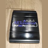 Černý kovový box s horizontálním frézováním povrchu. Na horní straně je bílý a fialový nápis ARTcessories™ a pod ním text SPLIT Com Pro Microphone Sp…