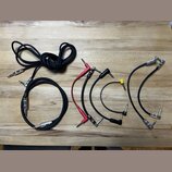 Sada různých audio kabelů s konektory typu jack položená na dřevěném stole. Je zde jeden dlouhý černý kabel, jeden kratší černý kabel s nápisem "KORD…