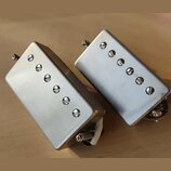 Dvě stříbrné humbuckerové snímače s kovovým krytem. Každý snímač má v horní části šest viditelných šroubů. Na krytech nejsou žádné viditelné značky a…