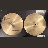 Dvě mosazné činely s jemným rýhováním povrchu. Levý činel nese nápisy „Byzance“ a „MEINL HOLANG MEINL“. Pravý činel nemá žádný viditelný nápis ani lo…