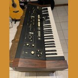 Černý digitální klavír v dřevěném šasi s nápisem YAMAHA SK20 SUPER ORGAN. Nástroj má bílé a černé klávesy, řadu posuvníků pro ovládání registru, něko…