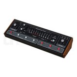 Černý syntetizátor s dřevěnými bočními panely. Na horním panelu jsou knoflíky, posuvníky a tlačítka s nápisy jako VOLUME, TUNE, BEAT, GLIDE a FILTER.…