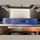 Modré rackové zařízení s nápisem MIDAS DL151 audio system I/O. Na předním panelu jsou umístěny kontrolky, displej a tlačítka s nápisy menu, select a…