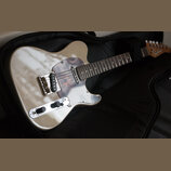 Elektrická kytara v krémové barvě s hnědým perleťovým pickguardem, položená v černém obalu. Na hlavě kytary je viditelné logo Epiphone. Nástroj má ch…