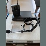 Sada bezdrátového mikrofonu v bílém polystyrenovém boxu. Obsahuje černý vysílač s logem Sennheiser a nápisem XS WIRELESS SENNHEISER, černý přijímač s…