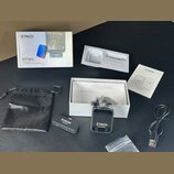 Sada bezdrátového mikrofonu v originálním balení. Obsahuje odesílač s nápisem SYNCO Receiver, přijímač s nápisem SYNCO Transmitter a větrný kryt z še…