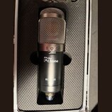 Kondenzátorový mikrofon v černém kufru s pěnovou výplní. Na těle je bílý nápis „the t.bone“ a níže označení modelu „SC-100“. V horní části je vidět s…