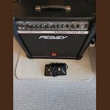 Černý kytarový kombo zesilovač s nápisy TRANSTUBE SERIES, STUDIO PRO 112 a PEAVEY. Na spodní části mřížky je červené logo ve tvaru stylizedého písmen…