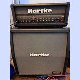 Kytarové kombo typu stack značky Hartke. Horní část tvoří zesilovač s ovládacími prvky, kde jsou viditelné nápisy INPUT, CRUNCH, VOLUME, BASS, TREBLE…