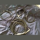 Čtyři černé instrumentní kabely různých délek položené na tmavé látce s motivem hvězd. Na jednom z konektorů nejdelšího kabelu je viditelný nápis Fen…