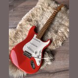 červená elektrická kytara s bílým pickguardem a hnědým hmatníkem. Na hlavě nástroje je viditelné logo Squier. Kytara má tři snímače, pětipositionní p…