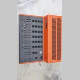 Oranžový míchací pult s černým ovládacím panelem. Na boku je uveden nápis STUDIO MIX B-30 a logo v červeném čtverečku. Panel obsahuje několik posuvní…