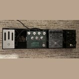 Tři kytarové efekty a jeden zesilovač sluchátek umístěné vedle sebe na černém podkladu. Zleva jsou vidět zařízení s nápisy ELEMENT cabamp headphone a…