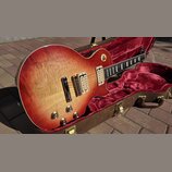 Elektrická kytara s tónem sunburst v červeně a žluté, umístěná v hnědém kufru s červeným plyšovým vnitřkem. Nástroj má dva humbuckery, čtyři otočné k…