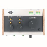 Audio rozhraní s bílým šasi a dřevěnými bočními panely. Na čelní straně je tmavý panel s nápisy VOLT 2 76, UA a ovládacími prvky Gain 1, Gain 2 a Mon…