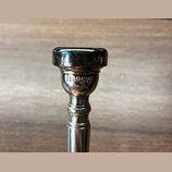 Detail horní části stříbrného kovového nástroje. Na povrchu je vyryt nápis YAMAHA JAPAN. Povrch vykazuje drobné škrábance a známky opotřebení.