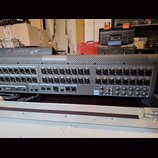 Šedý rackový stagebox s řadou vstupních konektorů. Na horní části je viditelné logo behringer a v pravé části jsou vstupy označené od IN 1 do IN 24.…
