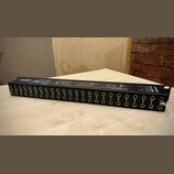 Černý rackový patchbay s řadou 24 zapojovacích jackových konektorů. Nad konektory jsou bílé nápisy s čísly od 1 do 24 a technické schéma zapojení. Na…