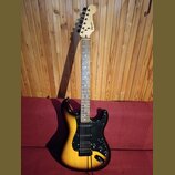 Elektrická kytara s telyem v barvě sunburst a černým pickguardem. Na hlavě hředu je viditelný nápis Squier. Nástroj má tři snímače a pětistupňový pře…