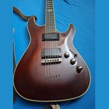 Hnědá elektrická kytara s dvojstupňovými humbuckery a chromovaným mostem. Na těle jsou tři otočné knofíky a jeden přepínač poloh snímačů. Povrch lako…