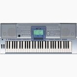 Stříbrný digitální klavír s černými a bílými klávesami. V horní části je umístěn modrý ovládací panel s displejem a nápisem YAMAHA. V pravé části nad…