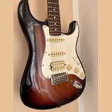 Elektrická kytara s telyem v provedení sunburst a bílým pickguardem. Nástroj má tři snímače s bílými kryty, tři otočné knofíky a jeden přepínač. Povr…