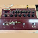 Bordeaux červený kytarový předzesilovač s efekty značky YAMAHA, model DG-Stomp. Zařízení má digitální displej zobrazující červené číslo 112 a řadu ov…