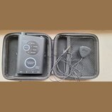 Černý přenosný efektový pedál v šedém zipovém pouzdře. Na zařízení jsou nápisy TONE, FEEDBACK CANCEL a přepínač s označením NATURAL, WARM, BRIGHT, NY…