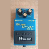 Modrý kytarový efekt s nápisy Blues Driver a BD-2w. Na spodní části je černý panel s logem BOSS a nápisem 技 WAZA CRAFT. Horní část obsahuje tři otočn…
