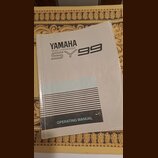 Bílá tištěná příručka s nápisy YAMAHA, MUSIC SYNTHESIZER a SY99. Ve spodní části je černý pruh s textem OPERATING MANUAL. Papír vykazuje známky opotř…