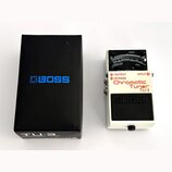 Bílá kytarový ladič s černým pedálem a displejem. Na přístroji jsou nápisy „OUTPUT“, „BYPASS“, „INPUT“, „Chromatic Tuner TU-3“ a logo „BOSS“. Vedle l…