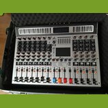 Stříbrný mixážní pult v přepravním kufru s pěnovou výplní. Na horní části je nápis MIXER a v centru se nachází displej s nadpisem 7-BAND STEREO GRAPH…