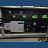 Černý rackový zesilovač značky NEXO s nápisem powered by YAMAHA a označením DIGITAL NXAMP4x4. Zařízení je umístěno v transportním kufru a má stříbrný…